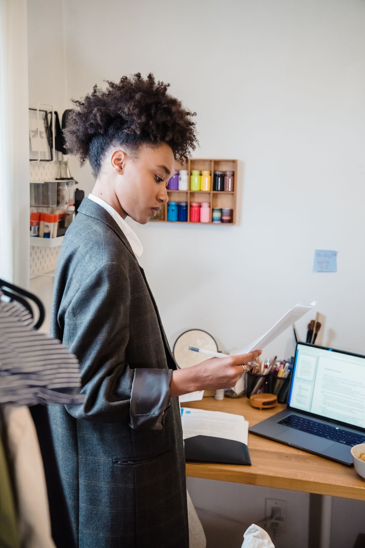 A person reviewing paperwork beside a laptop